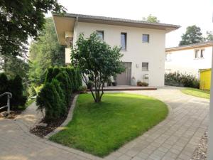una casa con un pequeño árbol en el patio delantero en Villa am Weinberg Waren Müritz en Waren