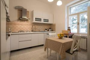 - une cuisine avec des placards blancs et une table avec un bol de fruits dans l'établissement Vintage Villa Magnolia, à Pula