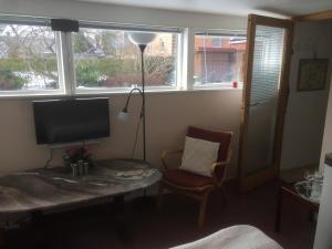 a living room with a table and a television and windows at Risskov Bellevue Guesthouse in Aarhus