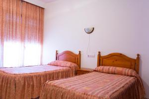 
a bedroom with two beds and two lamps at Hotel Alfar in Montilla
