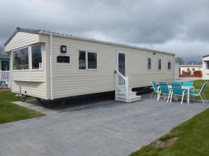 a small white trailer with chairs and a patio at Flamingo Land - Woodlands W42 in Kirby Misperton