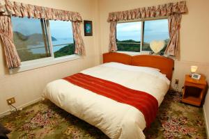 una camera da letto con un grande letto con due finestre di Koibito Misaki Pension Marine Mates a Izu