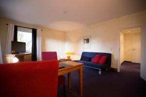 a living room with a blue couch and a red chair at Hotel Bürkle in Fellbach