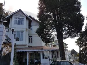 a white house with a car parked in front of it at Villa Everest in Darjeeling