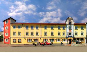 a large yellow and red building with people in front of it at Hotel Plankl in Altötting