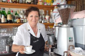 a woman holding a cup of coffee in front of a blender at Affittacamere Porticciolo in Castelnuovo del Garda
