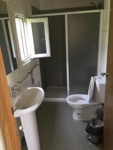 a bathroom with a sink and a toilet and a window at N`Guembú Nature Resort in Porto Alegre