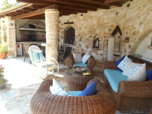 a patio with wicker furniture and a stone wall at Gidalia Villa in Gouvia