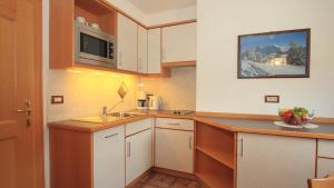 een kleine keuken met witte kasten en een wastafel bij Bed and Breakfast Iman in Santa Cristina in Val Gardena