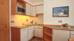 a small kitchen with white cabinets and a sink at Bed and Breakfast Iman in Santa Cristina Gherdëina