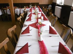 una larga mesa con servilletas rojas y banderas rojas en ella en Gasthaus ,,Zum schwarzen Bär", en Güsten