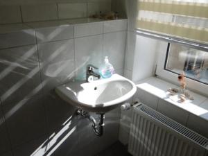 lavabo blanco en un baño con ventana en Gasthaus ,,Zum schwarzen Bär", en Güsten