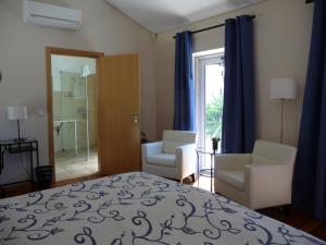 a bedroom with a bed and two chairs and a window at Casa Águas Mansas in Cadima +22 photos