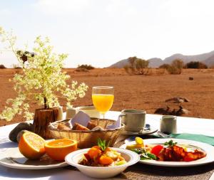 stół z talerzami jedzenia i szklanką soku pomarańczowego w obiekcie Namib Naukluft Lodge w mieście Solitaire