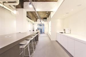 a kitchen with white cabinets and a long bar with stools at Hostel Haru in Seoul