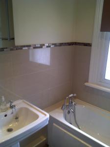uma casa de banho com um lavatório e uma banheira em De Parys Guest House - Fully Airconditioned em Bedford