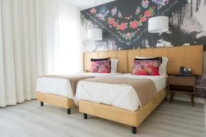 two beds in a bedroom with flowers on the wall at Hotel Magic in Nazaré