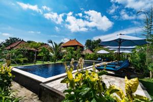 a resort pool with chairs and an umbrella at The Cozy Villas Lembongan in Nusa Lembongan