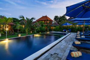a swimming pool with blue umbrellas and a resort at The Cozy Villas Lembongan in Nusa Lembongan