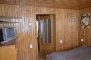 ヤレムチャにあるУ Любчикаの木製の壁のベッドルーム(テレビ、ベッド付)