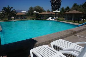 a swimming pool with two white chairs in front of it at Cabañas 4 Esquinas in La Serena