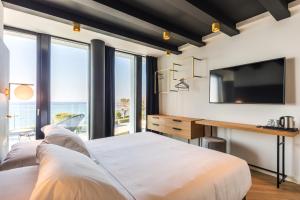 a bedroom with a bed and a desk with a television at MaisonMe Boutique Hotel in Bardolino