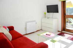 a living room with a red couch and a tv at Cozy Apartment with Terrace, Air Cond, Free Parking in Porto