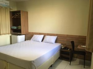 1 dormitorio con 1 cama blanca y 1 silla en Pousada Sumaré, en Caruaru