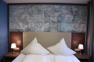 a bed with white pillows and a painting above it at Markthotel Warendorf in Warendorf