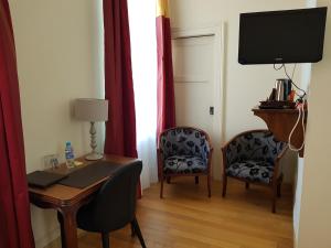 a room with a desk and two chairs and a television at LOGIS - Château de la Motte - Hôtel & Restaurant in Liessies