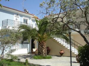 una palmera frente a una casa blanca en Dryoussa Apartments, en Pythagoreio