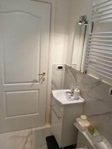 a white bathroom with a sink and a door at B&B Casa Nizza in Turin