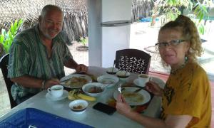 a man and a woman sitting at a table eating food at Naaval Beach Villa & Rooms in Batticaloa