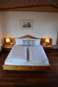 uma cama com lençóis brancos e almofadas num quarto em Hotel Eden Guesthouse em Marlengo
