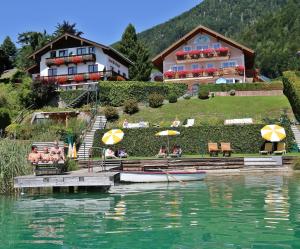 a hotel on the shore of a lake with people sitting under umbrellas at Haus Seeromantik in St. Wolfgang