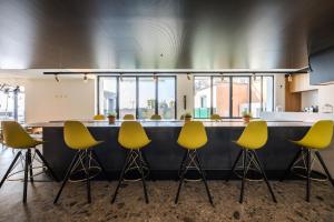 a bar with yellow chairs in front of a counter at MaisonMe Boutique Hotel in Bardolino