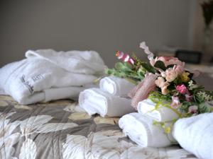 una pila de toallas y flores en una cama en CASA FELICE Suite Room, en Taranto