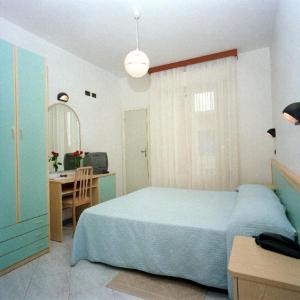 - une chambre avec un lit bleu et un bureau dans l'établissement Hotel La Pineta, à Riccione