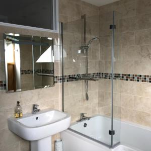 a bathroom with a sink and a glass shower at East Trayne Holiday Cottages in South Molton