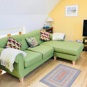 a green couch sitting in a living room at East Trayne Holiday Cottages in South Molton