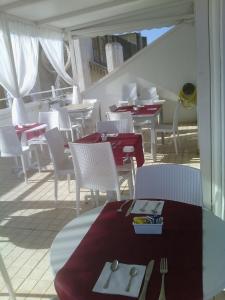 a restaurant with white chairs and tables with red table cloth at Hotel Città Bella in Gallipoli