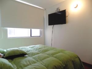 um quarto com uma cama e uma televisão de ecrã plano na parede em Room and private Bathroom at Chapinero Alto em Bogotá