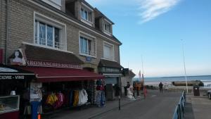 a store on a sidewalk next to the beach at Arroplace in Arromanches-les-Bains