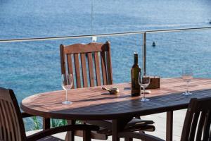 a wooden table with a bottle of wine and two glasses at Seaview Suite Lissa in Vis