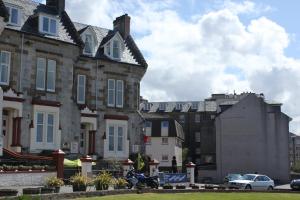 奥本Corran House Guest House的停在房子前面的摩托车上的人