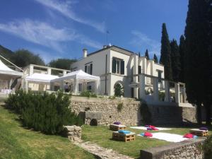 a large white house with a garden in front of it at Washington Apartments al Vittoriale in Gardone Riviera