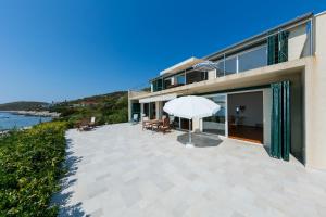 a house with a patio with an umbrella at Seaview Suite Lissa in Vis