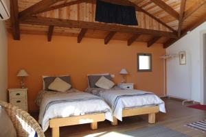 Habitación con 2 camas, paredes de color naranja y techos de madera. en Off The Square, en Safed