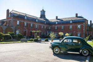 an old green car parked in front of a building at LOGIS - Château de la Motte - Hôtel & Restaurant in Liessies