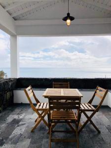 duas cadeiras e uma mesa num pátio com o oceano em Casa Avó Amélia em Madalena